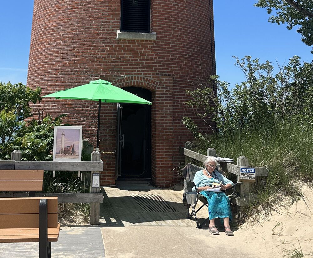 Woman sitting in front of lighthouse