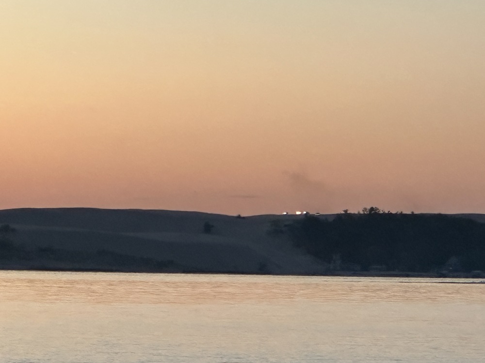 Headlights on dunes at sunset