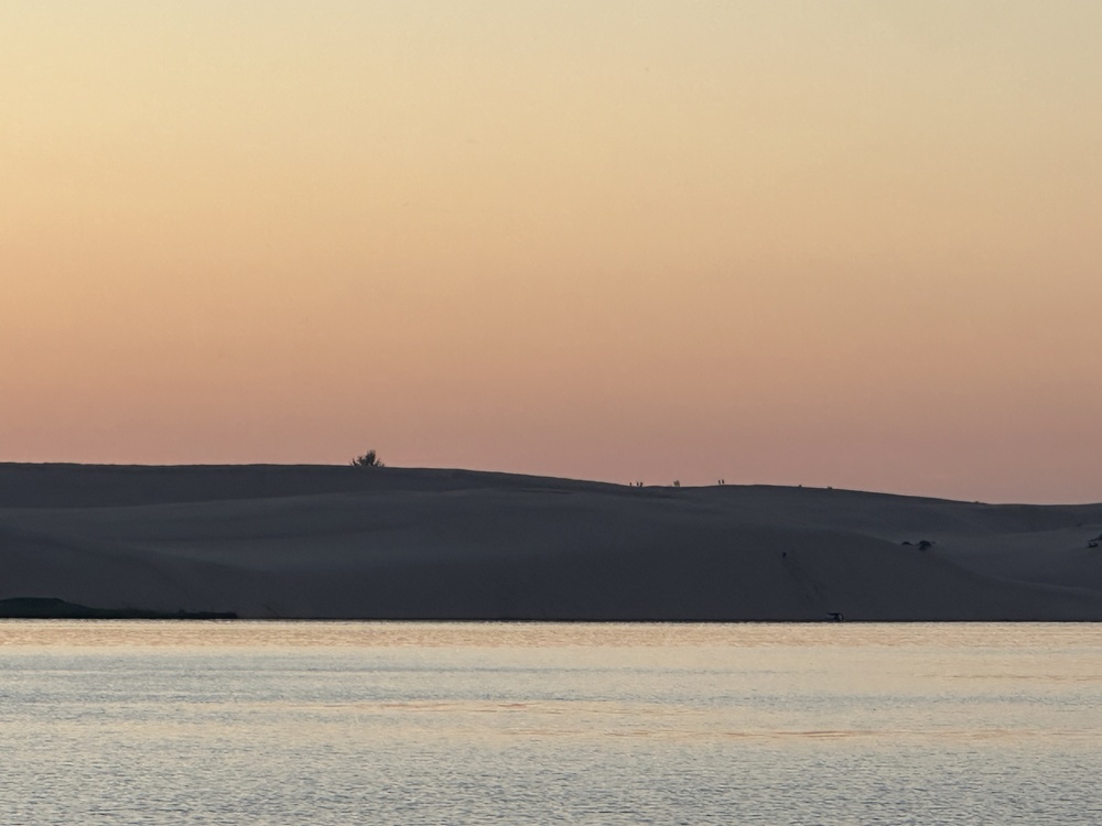 People on dunes at sunset